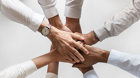 Several hands in a teamwork huddle.